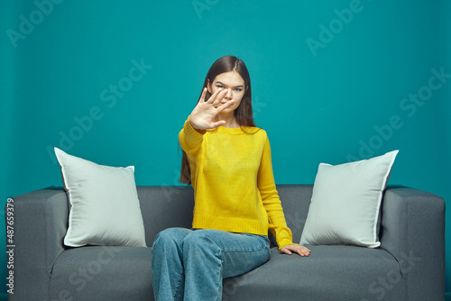Serious young girl do stop gesture, protest against domestic violence, say no, reject unpleasant offer sitting on sofa