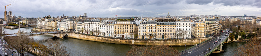 Seine embankment in Paris. View of the island  Saint-Louis, the bridge de la Tournelle and Sully Bridge. Beautiful breathtaking panoramic cityscape of the majestic famous ancient French city.