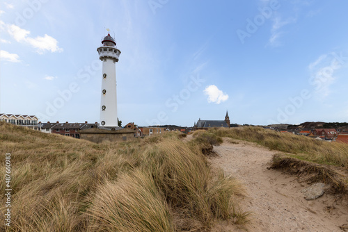 White lighthouse in the dunes in the small village of Egmond aan Zee in the Netherlands.
