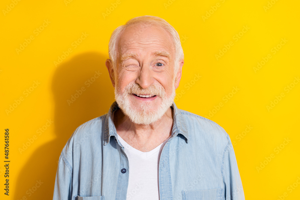 Portrait of attractive cheerful grey-haired man good mood winking isolated over bright yellow color background Portrait of attractive cheerful grey-haired man good mood winking isolated over bright yellow color background
