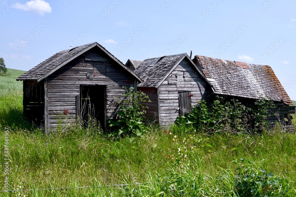 abandoned farm buildings are crumbling in a field abandoned farm buildings are crumbling in a field