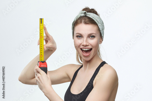 beautiful blonde girl holds a measuring tape in her hands. measurement concept about penis size