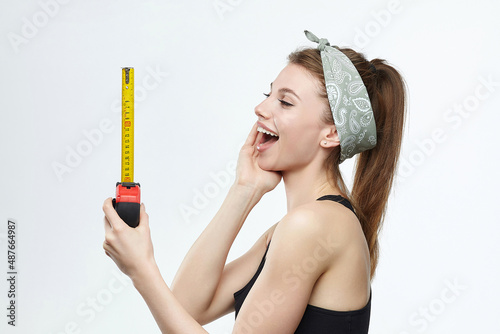 beautiful blonde girl holds a measuring tape in her hands. measurement concept about penis size photo