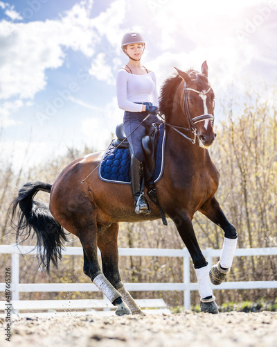 Fotografie Young teen rider girl riding horse at the field.