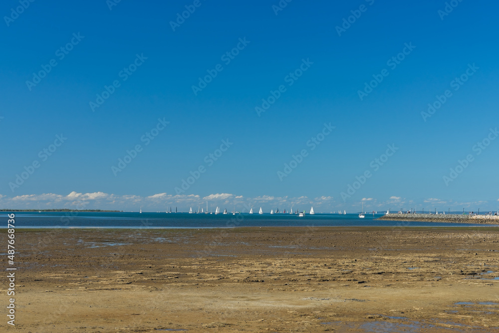 Minimalist image. View from the shore of distant sailing boats on the bay at Wynnum, Queensland, Australia. 