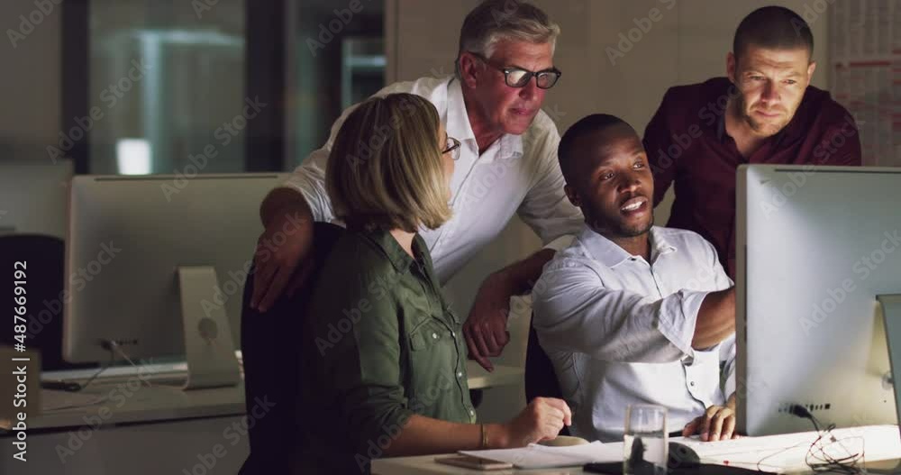 Business group of diverse colleagues using computer and discussing work at a table during a late night in a modern office
