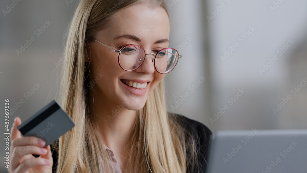 Smiling caucasian business woman shopping online using laptop paying with credit bank card buy order booking remotely net. Happy 30s female with glasses purchas website internet banking secure system Smiling caucasian business woman shopping online using laptop paying with credit bank card buy order booking remotely net. Happy 30s female with glasses purchas website internet banking secure system