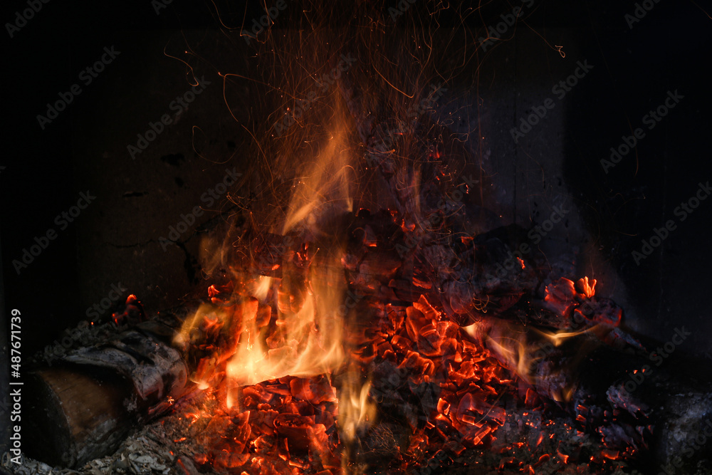 Bright burning wood in a fireplace with sparks close-up Bright burning wood in a fireplace with sparks close-up