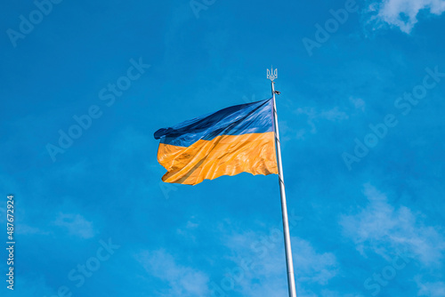 Ukrainian bicolor yellow blue national flag with trident emblem waving in wind against sky, National flag of ukraine on sunny day photo