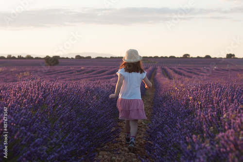 niña pelirroja con sombrero de paja jugando entre lavandas en verano al atardecer. Brihuega