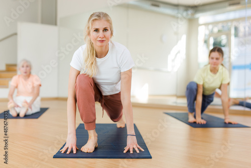 Sport and healthy lifestyle concept - females doing stretching workout during group training in fitness studio