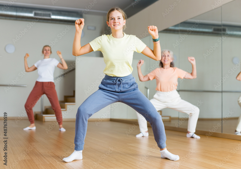 Fototapeta premium Smiling teen girl with family enjoying active dances in modern dance studio