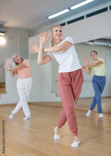 Portrait of positive smiling european woman and people dancing in modern studio