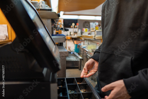 Young boy dressed in black counting money from a bar cash