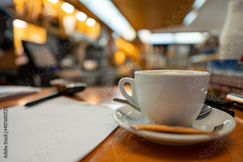 Cup of coffee placed on the wooden counter of a bar