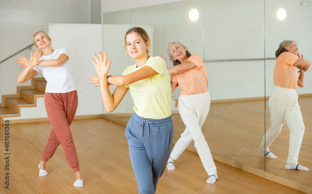 Teenage girl dancing with her family, mother and grandmother, in studio.