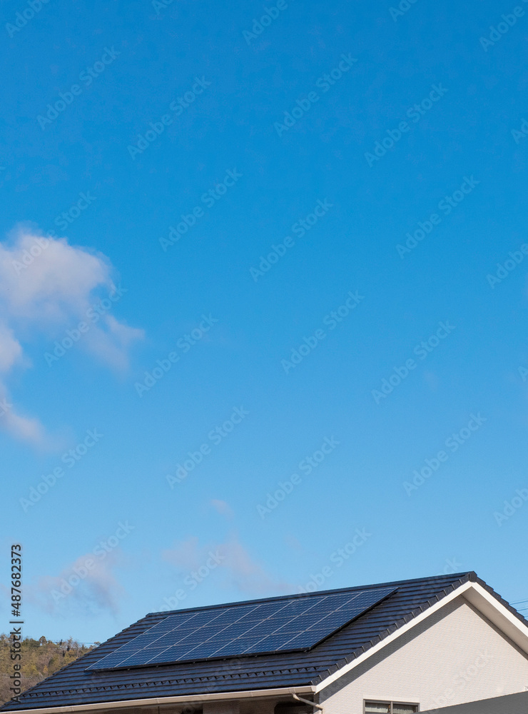 太陽光発電。太陽光パネルが設置された住宅の屋根と快晴の青空。