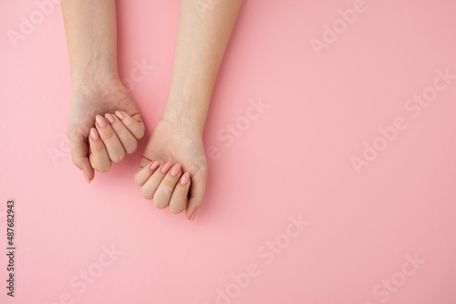 Woman showing nude manicure on pastel pink background photo
