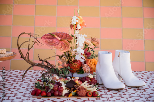 White wedding boots, tropical floral arrangement and charcuterie board on table