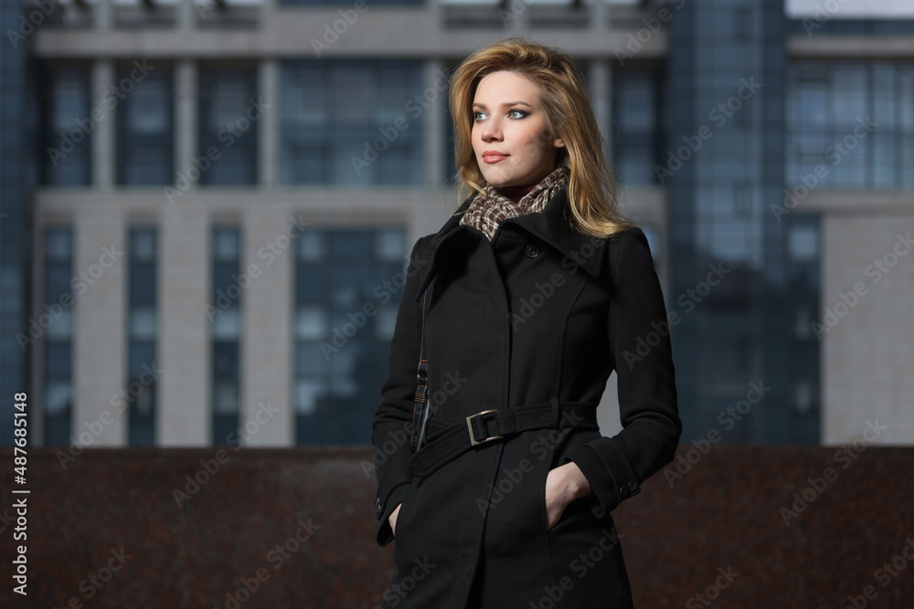 Young woman in black coat walking on city street Young woman in black coat walking on city street