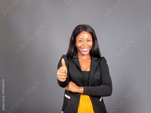 Canvas Print Beautiful young dark haired black woman in eloquent clothing with a happy expression how thump up for agreement sign with success business concept