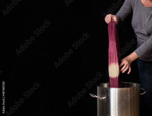 A woman's hands shows a natural dye called cochineal that is used to dye fibers such as yarn and fabrics, against a solid black background.