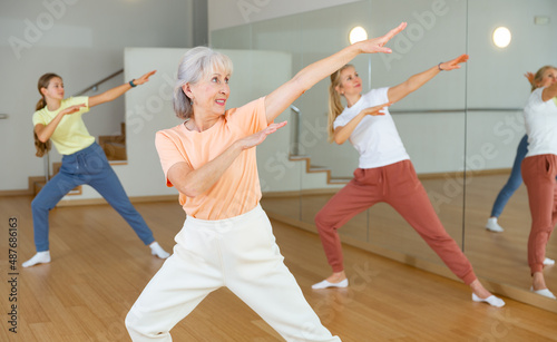 Ordinary active females exercising dance moves in dance center