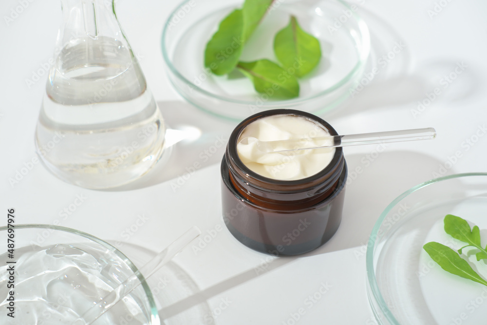 Cosmetic container with green herbal leaves and scientific glassware, Research and develop natural organic beauty skincare product, copy space, banner Cosmetic container with green herbal leaves and scientific glassware, Research and develop natural organic beauty skincare product, copy space, banner