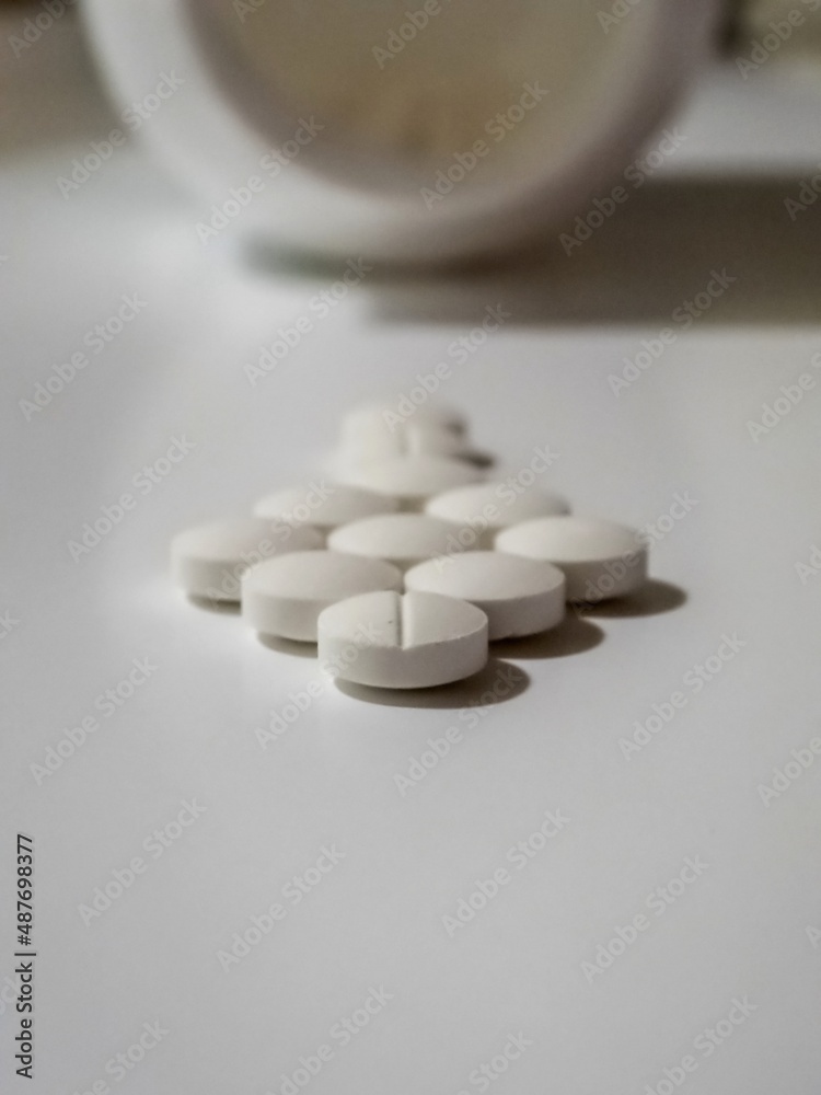 White Tablets Of Medicine And A Bottle In The Background White Tablets Of Medicine And A Bottle In The Background