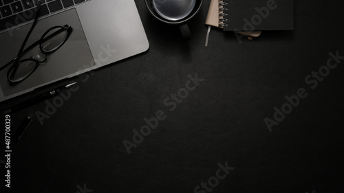 Modern office desk with laptop and copy space on black background. top view