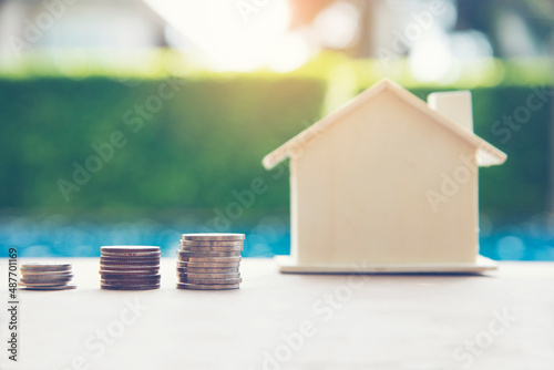 Women hand holds a coin in a piggy bank for future home purchases. Save money. Economic concept