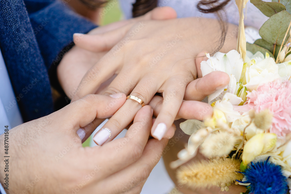 Fototapeta premium groom putting wedding ring on bride, close up