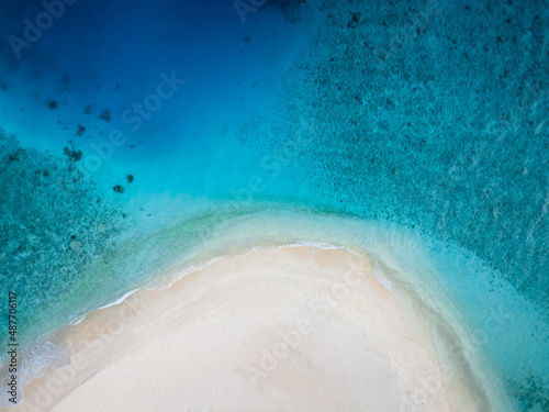 Perfect beach for holidays vacation with white sand and turquoise blue transparent water. Top down aerial view from drone. Pristine tropical island in Maldives. Abstract travel copy-space background.