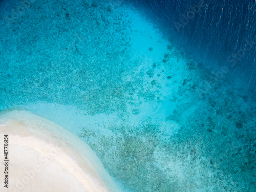 Perfect beach for holidays vacation with white sand and turquoise blue transparent water. Top down aerial view from drone. Pristine tropical island in Maldives. Abstract travel copy-space background.