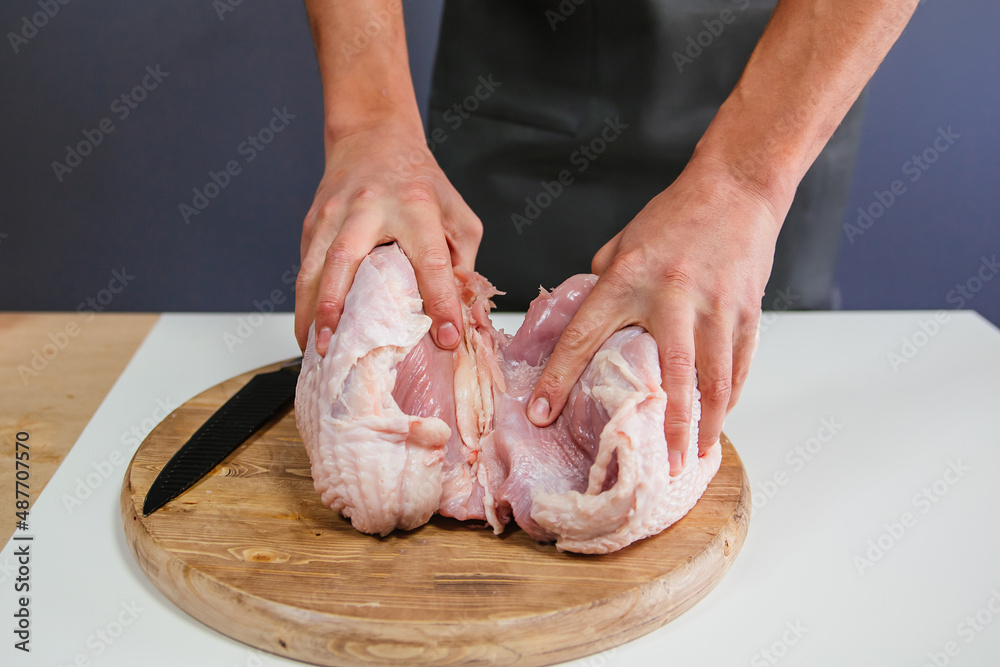 Male hands cut a turkey breast with a knife. Carcass of poultry meat.