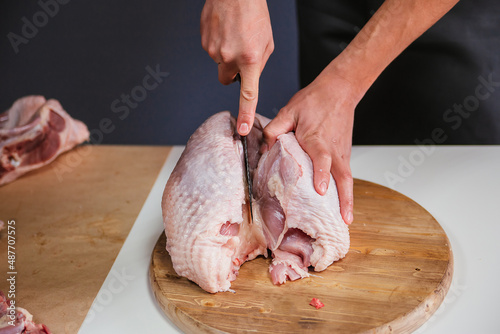 Male hands cut a turkey breast with a knife. Carcass of poultry meat.
