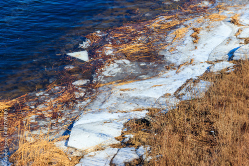 Bank of a wide river with pieces of ice during an ice drift