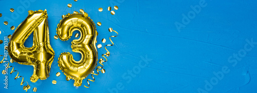 golden foil balloon number forty three. Birthday or anniversary card with the inscription 43. blue concrete background. Anniversary celebration. Banner.