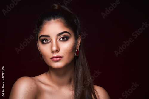 portrait of Hindu girl who advertises luxury jewelry isolated on dark background. Jewelry concept