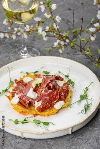 dish with potato and hammon pancake and dried peppers on a gray background with a glass of wine vertically
 photo