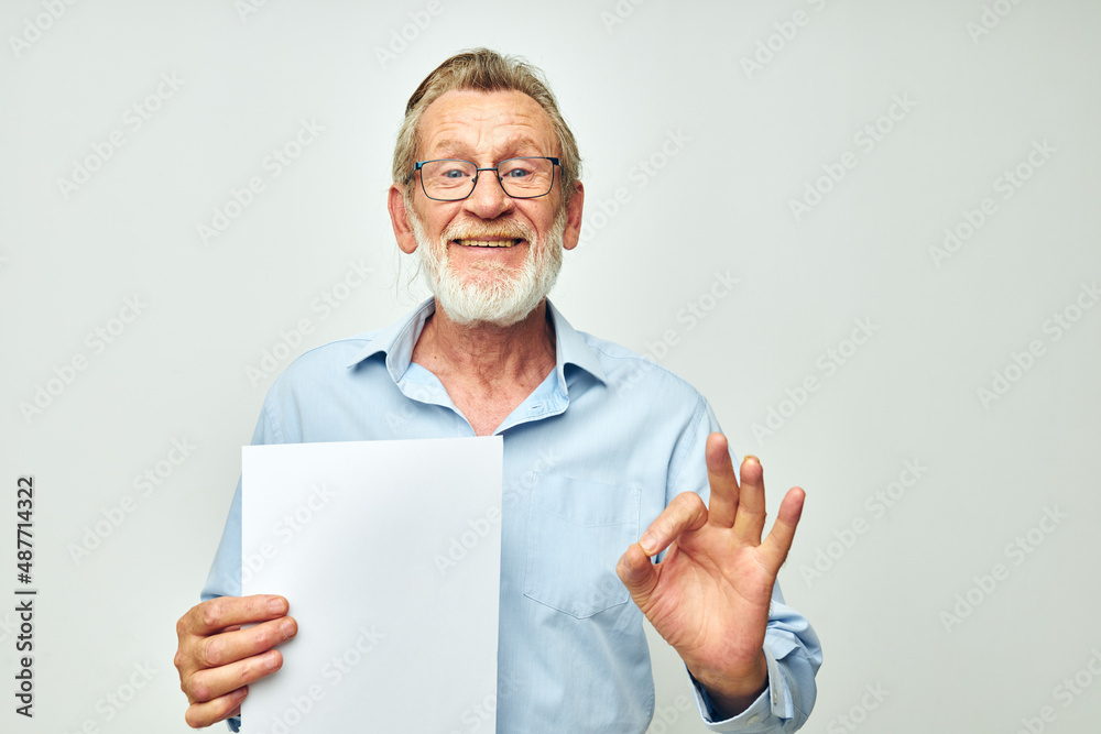 Senior grey-haired man blank sheet of paper gesture hands smile light background Senior grey-haired man blank sheet of paper gesture hands smile light background