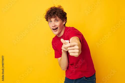 Young curly-haired man wearing a red t-shirt medical mask on the face posing isolated background unaltered