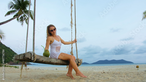 Sexual woman spends her vacation at the seaside. The girl is swinging on a swing. Concept travel, walks, rest, natural beauty, tropical resort traveling tourism summer holidays