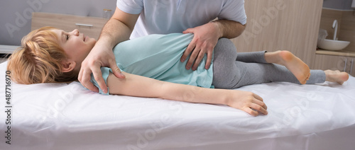 An osteopathic doctor is working with the child. Work on twisting the spine. Teenage girl patient chiropractor. Posture correction