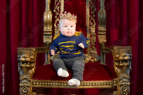 Funny kid for the royal crown on the royal throne. photo