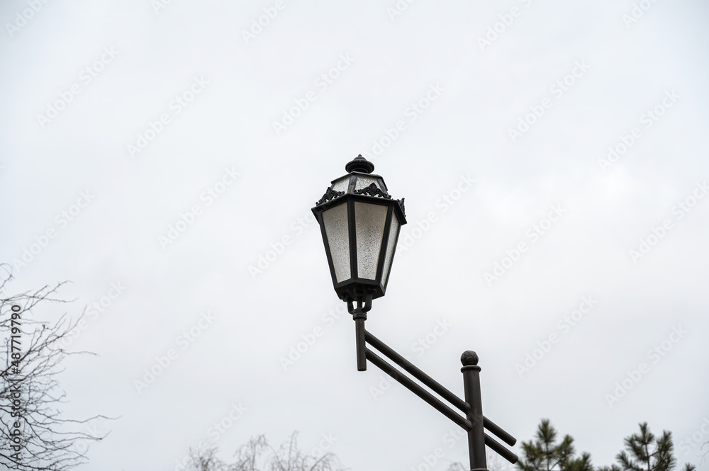 An antique-style street lamp against an overcast sky. It's cloudy. Daytime. An antique-style street lamp against an overcast sky. It's cloudy. Daytime.