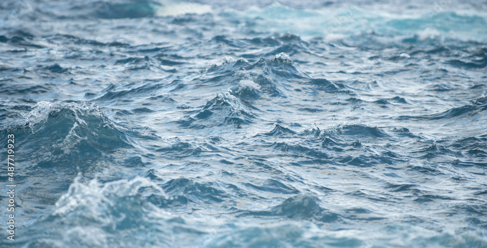 Calm sea water surface texture with splashes and waves. Abstract nature background. Background of aqua ocean water surface.