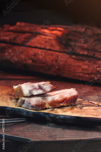 Smoked pork ham bio traditionally rustic dish, on a hand-made wood derving or cutting board, spicy smoked bacon traditional preparation at home photo