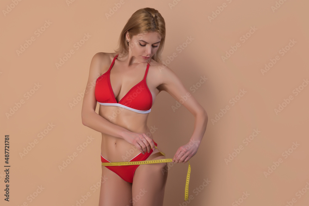 Naklejka premium Attractive caucasian woman measuring her buttocks isolated background.
