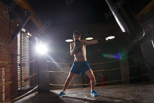 A boxer trains in the gym strikes a punching bag.